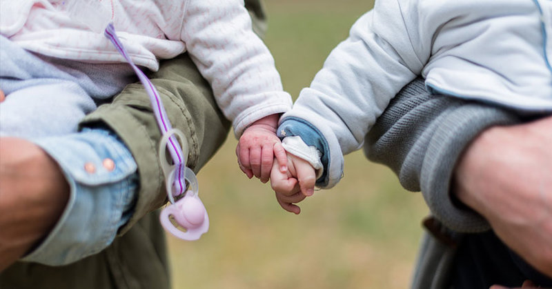 Zwei Babies auf den Armen ihrer Eltern