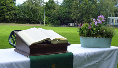 Aufgebauter Altar mit Bibel und Blumenschmuck auf einem Fußballfeld - Copyright: Karen Diehn