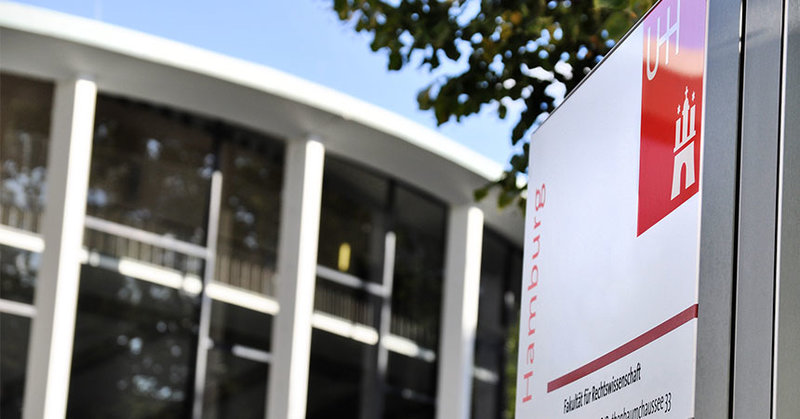Universitätslogo auf einem Wegweiser vor dem Audimax