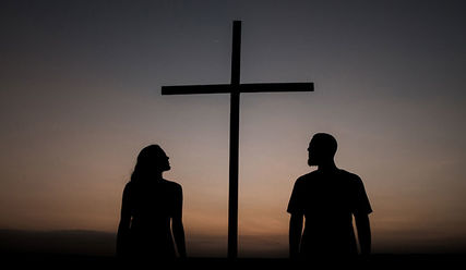 Zwei Menschen im Sonnenuntergang vor einem Kreuz - Copyright: Junior Reis/Unsplash