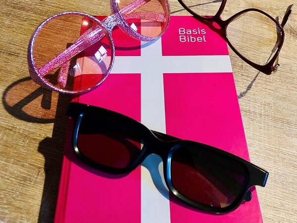 Rotes Buch mit Kreuz auf dem Deckel, Titel Basis-Bibel, darauf zwei Brillen, 1 Sonnenbrille - Copyright: Saskia Albers