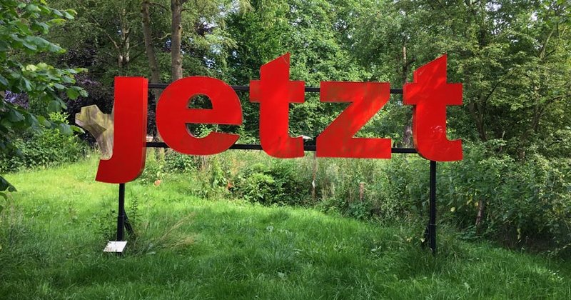 "jetzt" – dieses Wort empfängt Besucher bei ihrer Ankunft