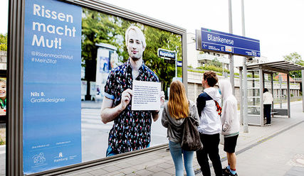 Drei Jugendliche schauen ein Plakat zu 'Rissen macht Mut' an - Copyright: Tobias Stäbler