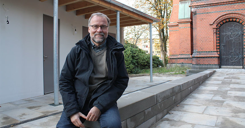 Pastor Martin Kaiser freut sich über die neuen Sanitäranlagen (links im Bild). Rechts ist der rückwärtige Eingang der Kreuzkirche zu sehen.