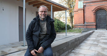 Pastor Martin Kaiser freut sich über die neuen Sanitäranlagen (links im Bild). Rechts ist der rückwärtige Eingang der Kreuzkirche zu sehen. - Copyright: © Hagen Grützmacher