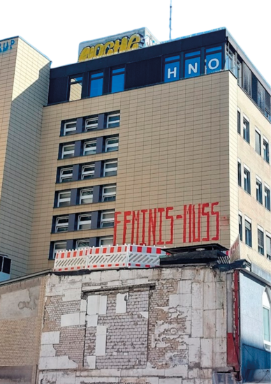 Gelbes Hochhaus mit Graffiti: FEMINIS-MUS
