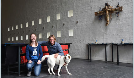 Zuhause in der Kirche: Münsterländer-Mix Tölpel mit Pastor Holger Janke und Praktikantin Mona Bürger - Copyright: Sabine Henning/kirche-hamburg.de