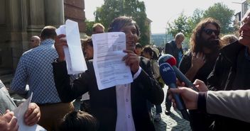 Der Sprecher der Gruppe, Romano Schneider, zeigt Abschiebungsbescheide