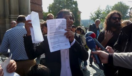 Der Sprecher der Gruppe, Romano Schneider, zeigt Abschiebungsbescheide