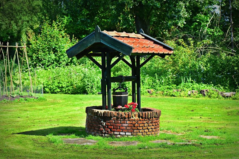 Brunnen im Garten mit hochgezogenem Eimer