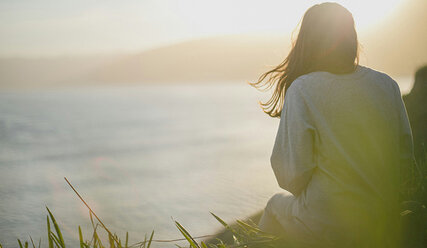 Frau auf einer Klippe blickt in Sonnenaufgang - Copyright: Unsplash, Artem Kovalev