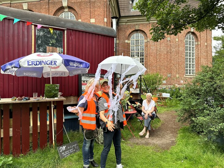 Diakonin Johanna-Maria Lühmann steht mit Marion Laux vor dem roten Bauwagen des Projekts