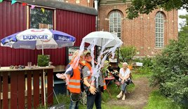 Diakonin Johanna-Maria Lühmann steht mit Marion Laux vor dem roten Bauwagen des Projekts - Copyright: Mutsa Chiwakata