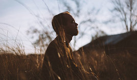 Mann sitzt auf einem Feld - Copyright: Pexels