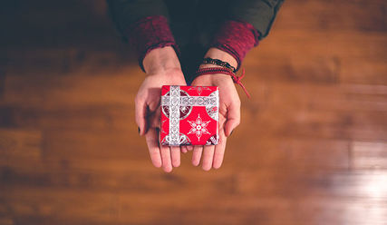 Zwei Hände halten ein Weihnachtsgeschenk - Copyright: Ben White / Unsplash